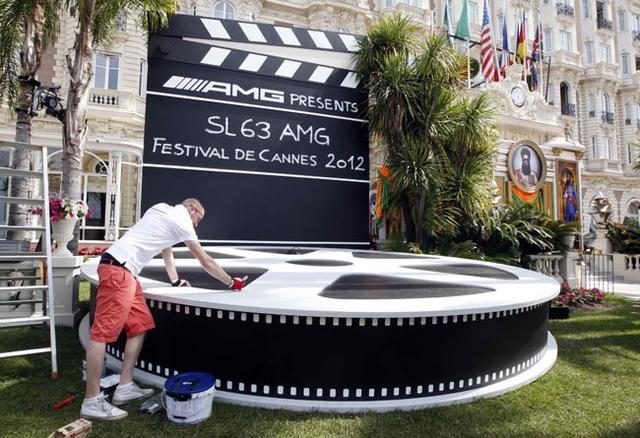 A worker paints a giant film reel of the 65th Cannes Film Festival in front of the Carlton Hotel on the eve of the start of the festival in Cannes