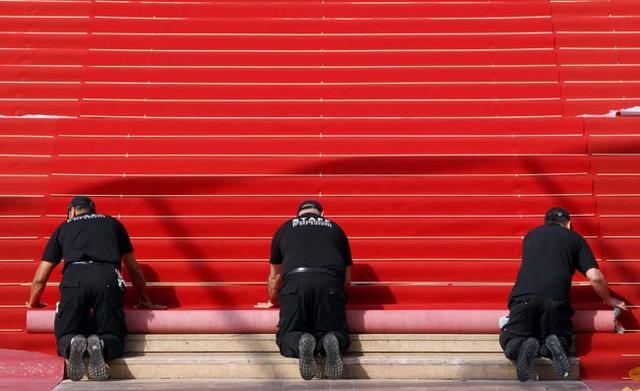 Workers install the red carpet in front of the main entrance of the Festival Palace in Cannes